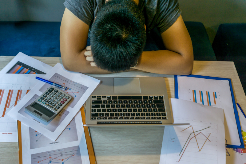 overwhelmed adult at desk with sales report
